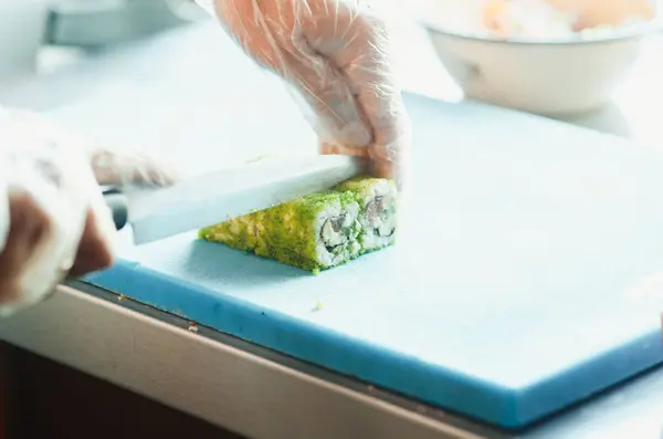 The cook makes a sushi roll with bamboo Mat cuts. The process of cooking sushi roll