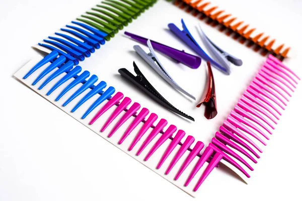Frame of multi-colored hair clips on a white background, in the center of the hair clips are large cool