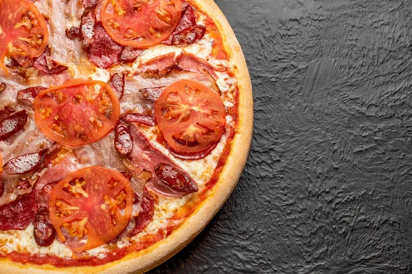 Four-meat pizza on a black background, tomato-based with mozzarella, bacon, ham, salami, hunting sausages and tomatoes,Delicious — Stock Image Four Meat Pizza Black Background Tomato Based Mozzarella Bacon Ham Stock Photo