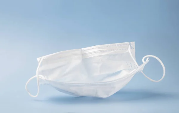 Typical 3-ply surgical mask to cover the mouth and nose. Surgical mask with rubber ear straps. Concept of medicine and healthcare, anti-virus procedures. Selective focus. Copy space