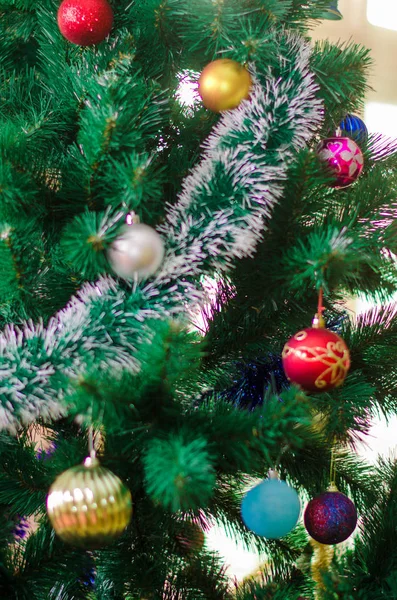 Closeup της κόκκινο μπιχλιμπίδι κρέμεται από ένα στολισμένο χριστουγεννιάτικο δέντρο — Φωτογραφία Αρχείου
