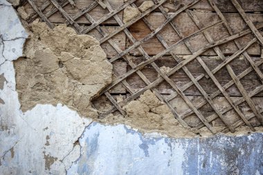 Eski bir evin duvarında alçı kabuğu soyulmuş. Kavram: Modern teknolojiye zıt.