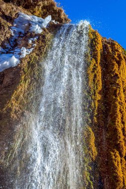 Eski karların kalıntılarıyla dağlarda bahar şelalesi.