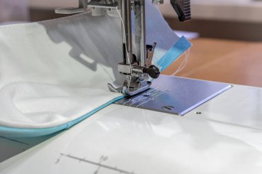 Evde yeniden kullanılabilir bir tıbbi maske dikiyorum. Dördüncü adım. Maskeyi dikiş makinesine dikiyorum. Kenar boyunca dikin..