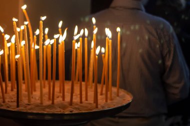 Kilise mumları kumlu bir şamdanda yakar..
