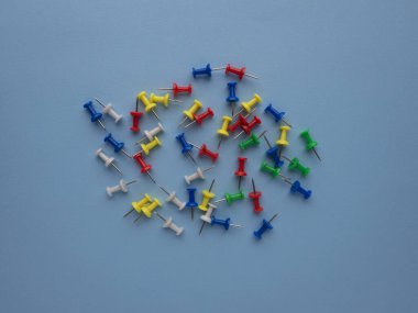 Farklı renkler mavi arkaplan görünümünde izole edilmiş ve kopyalama alanı olan iğneleri ittirir.