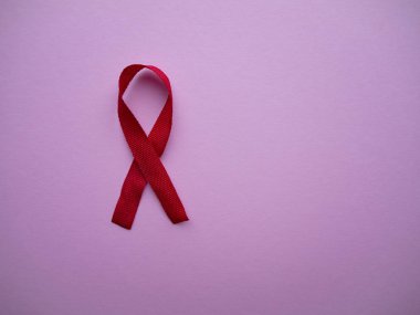 Kırmızı kurdele, AIDS ve Hiv 'le birlikte yaşayanların farkındalık ve desteğinin evrensel sembolü ve kopyalama alanı olan pembe bir zemin üzerinde yaşıyor. 1 Aralık Dünya Yardım Günü, HIV hastalığı kampanyası.