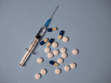 İlaç ve mavi beyaz tıbbi haplarla dolu şırınga ve kapsüller mavi arka plan görünümünde metin için kopya alanı ile birlikte.