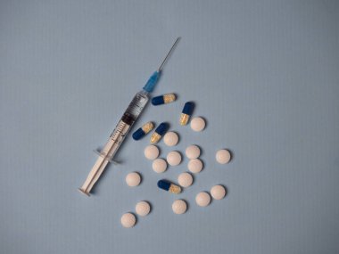 İlaç ve mavi beyaz tıbbi haplarla dolu şırınga ve kapsüller mavi arka plan görünümünde metin için kopya alanı ile birlikte.