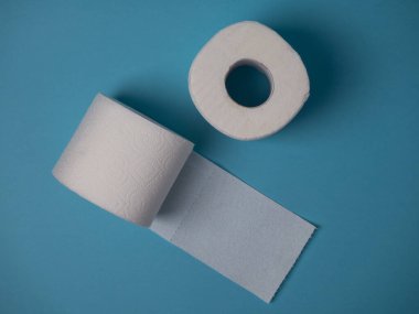 Mavi arka planda iki rulo beyaz tuvalet kağıdı..