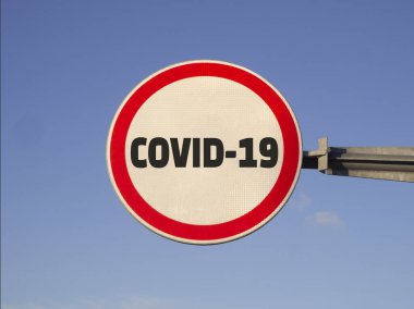 COVID-19 alarm konsepti. Mavi gökyüzü arka planında yuvarlak kırmızı yol işareti.