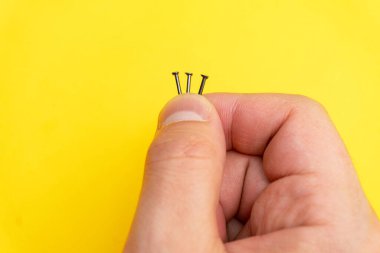 Close up of nails in mans fingers on yellow background