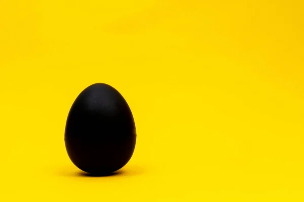 Black egg on yellow background