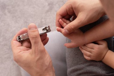 Process of cutting nails at the fingers of small baby with clipper