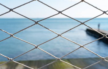 View at the blue sea through white ropes