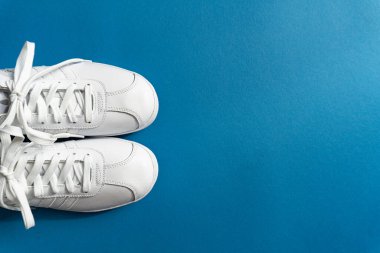 Klasik mavi arka planda beyaz unisex ayakkabılar.