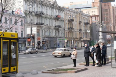 Kiev, Ukrayna, 27 Mart 2020, insanlar otobüs durağındaki otobüslerde koruyucu maskeler takıyor.,