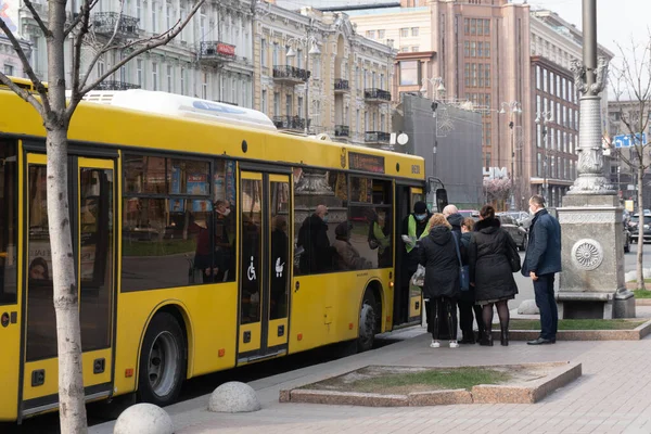 乌克兰基辅，2020年3月27日，街道上戴防护面罩的人们在巴士站为公共汽车浇水, — 图库照片