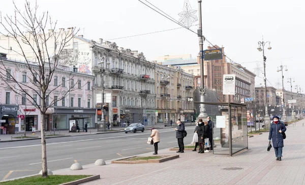 Киев, Украина, 27 марта 2020 года, люди в масках ждут автобус на автобусной остановке — стоковое фото
