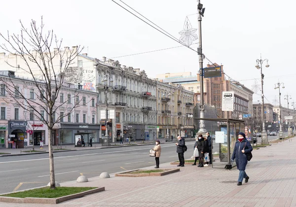 Киев, Украина, 27.03.2020, люди в защитных масках ждут автобус на автобусной остановке — стоковое фото