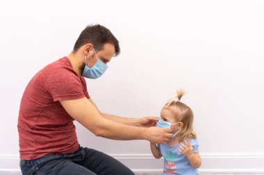 Adam çocuğuna koruyucu maske takıyor.