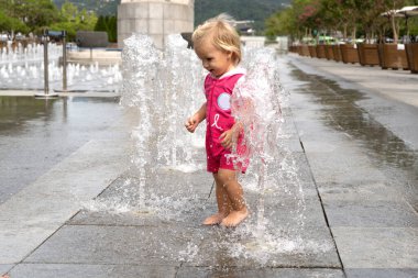 Yaz günü fıskiyede oynayan beyaz, şirin bir bebek.,