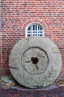 Old Millstone Doğu Frizya 'da bir yel değirmeninin önünde duruyor, Aşağı Saksonya, Almanya 