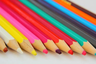 Renkli kalemler beyaz kağıt üzerinde bir satırda yatıyor