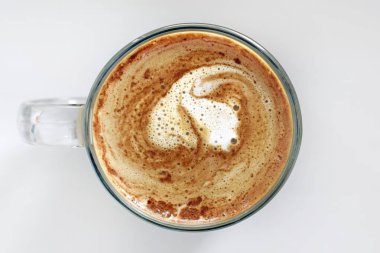 Gri arka planda bir fincan demlenmiş kahve, üst manzara. Yuvarlak kahve, cam bardak. Sütlü ve köpüklü iştah açıcı kahve kahvaltıda sıcak bir içecek..