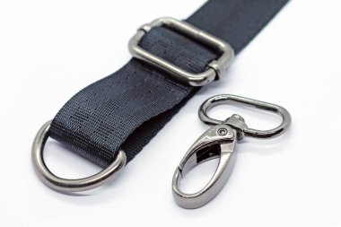 Çanta ve sırt çantaları yapmak için dikiş metal parçaları. Karabina, beyaz arka plan üzerinde koyu nikel renkte yarım halka ve uzunluk ayarlayıcısı. Çanta farklı yapmak için siyah bant.