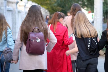 Kharkiv, Ukrayna - 28 Eylül 2019: Beş genç kız, üniversitede derslerle birlikte cadde boyunca yürüyor. Arkadan bak. Açık bir sonbahar günü, kot giyen kızlar, kazaklar, yarı sezonluk paltolar.. 