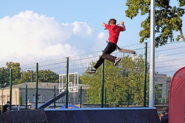 Kharkiv, Ukrayna - 8 Ağustos 2019: Çocuk parkta scooter sürüyor. Sıçrama tahtasından atladı, havada bir numara yaptı. Scooter 'ı olan bir çocuk. Gençler için parkta aktif eğlence.