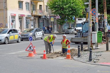 Batumi, Gürcistan - 4 Haziran 2019: Yolda bir çukurda duran yeşil yelekli iki işçi. Asfalt yolda yol konileri ve yol çalışması işaretleri, kamu hizmetleri işçileri. Kanalizasyon onarımı.