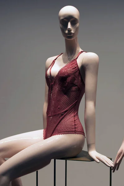 The mannequin sits in red women\'s underwear in a shop window with illuminated bottom. Delicate red lingerie on the showcase
