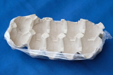 Boş yumurta tepsisi kapat. Mavi arka planda selofanda karton yumurta tepsisi. Kullanılmış kağıt yumurta kabı..