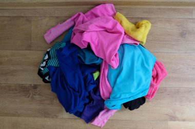 Zemindeki çok renkli şeyler bir yığın içinde. Yıkanmak için kıyafetler. Renkli çamaşırları yıka. Evde karışıklık var.