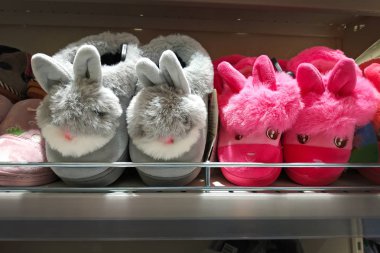 Yumuşak terlikler, gri ve pembe tavşanlar. Mağaza raflarında iç terlikler. Çocuklar için yumuşak renkli terlikler.