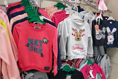  Mağazada çok sayıda çocuk kıyafeti var. Çocuklar için modaya uygun yeni bir kıyafet koleksiyonu bir butikte asılı. Parlak kazaklar Noel teması