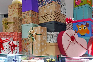 Alışveriş merkezinde fiyonklu renkli hediye kutuları. Noel hediyelerini süslemek için karton kutular. Birçok hediye kutusu birbirinin üstünde duruyor..