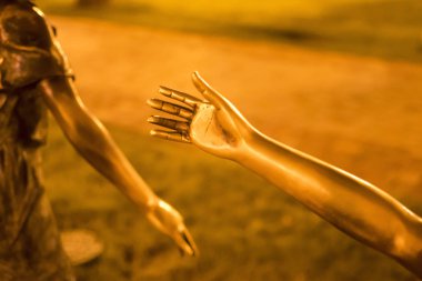 Bir parça, bir heykel eli, başka bir insana uzanan bronz bir el, palmiye. Kavram. Gece vakti.