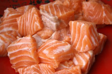 pieces of red salmon fish on a red plate. slices of fresh fish fillet on a dish.