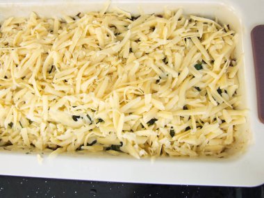 vegetable casserole in a baking dish sprinkled with grated cheese top view cooking process, vegetarian dish