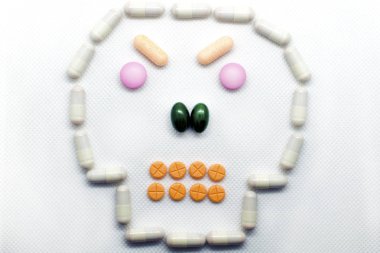 The concept of health care, medical devices, treatment of diseases, the benefits and harm of tablets. form of the skull paved with pills on a white background, negative emotion