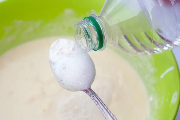 Baking soda is quenched with vinegar. A spoon of soda and a plastic bottle. The process of making dough using baking soda.