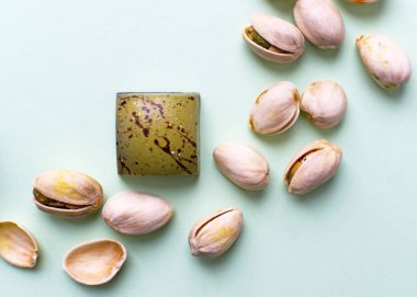 Açık yeşil arka plan manzaralı fıstıklı çikolata şekeri. Fındıklı lezzetli tatlılar, fıstıklı çikolatalar.