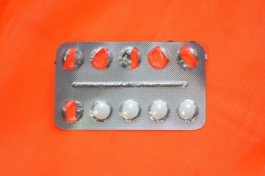 Turuncu arka planda beyaz haplar olan gri kabarcıklar. İçinde hap olan yarısı boş bir paket. Yuvarlak beyaz alerji hapları.