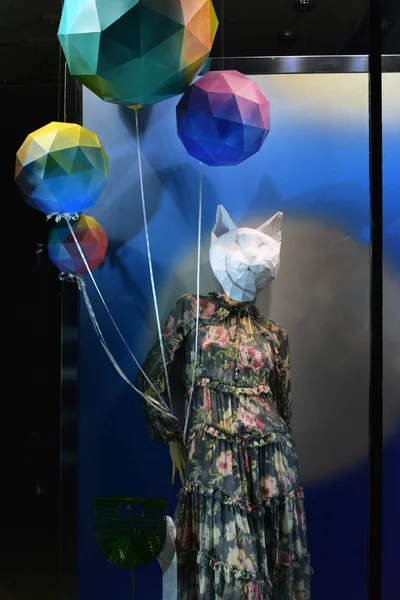 Female mannequin in a dress with a cat mask and balls. Squirrel mask made of paper on a mannequin. Decoration showcases fashionable clothes.