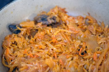Stewed white cabbage with mushrooms in a frying pan. Fried cabbage with spices. Vegetable dish for vegetarians.