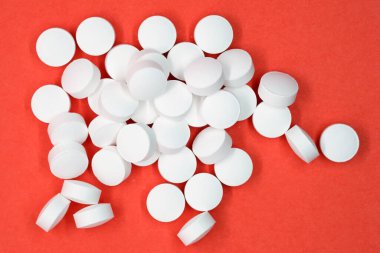 Beyaz yuvarlak haplar üst görünüm. Turuncu arka planda tablet şeklinde diyet takviyesi. Aşırı dozda ağrı kesici.