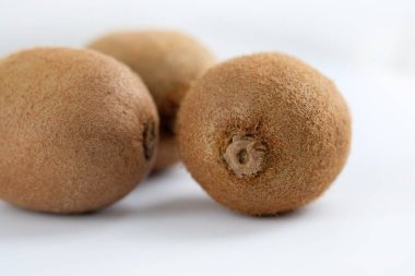 Beyaz arka planda tam üç kivi meyvesi. Olgun kivi meyveleri yakın çekim.